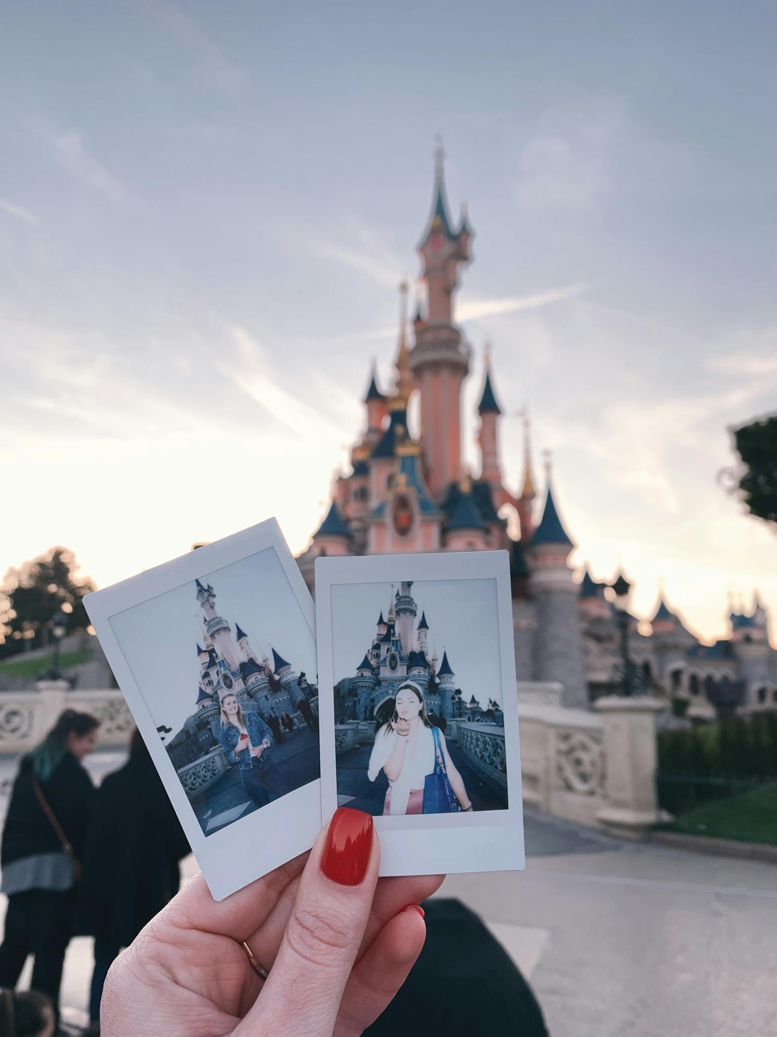 Polaroids held in front of Sleeping Beauty Castle at Disneyland Paris, a perfect travel memory.