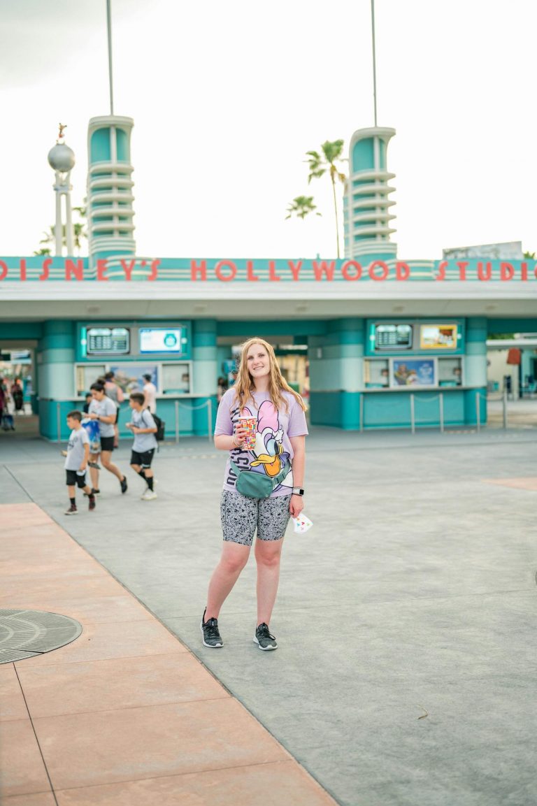 Smiling woman stands at Disney's Hollywood Studios entrance, embracing a joyful tourist experience.