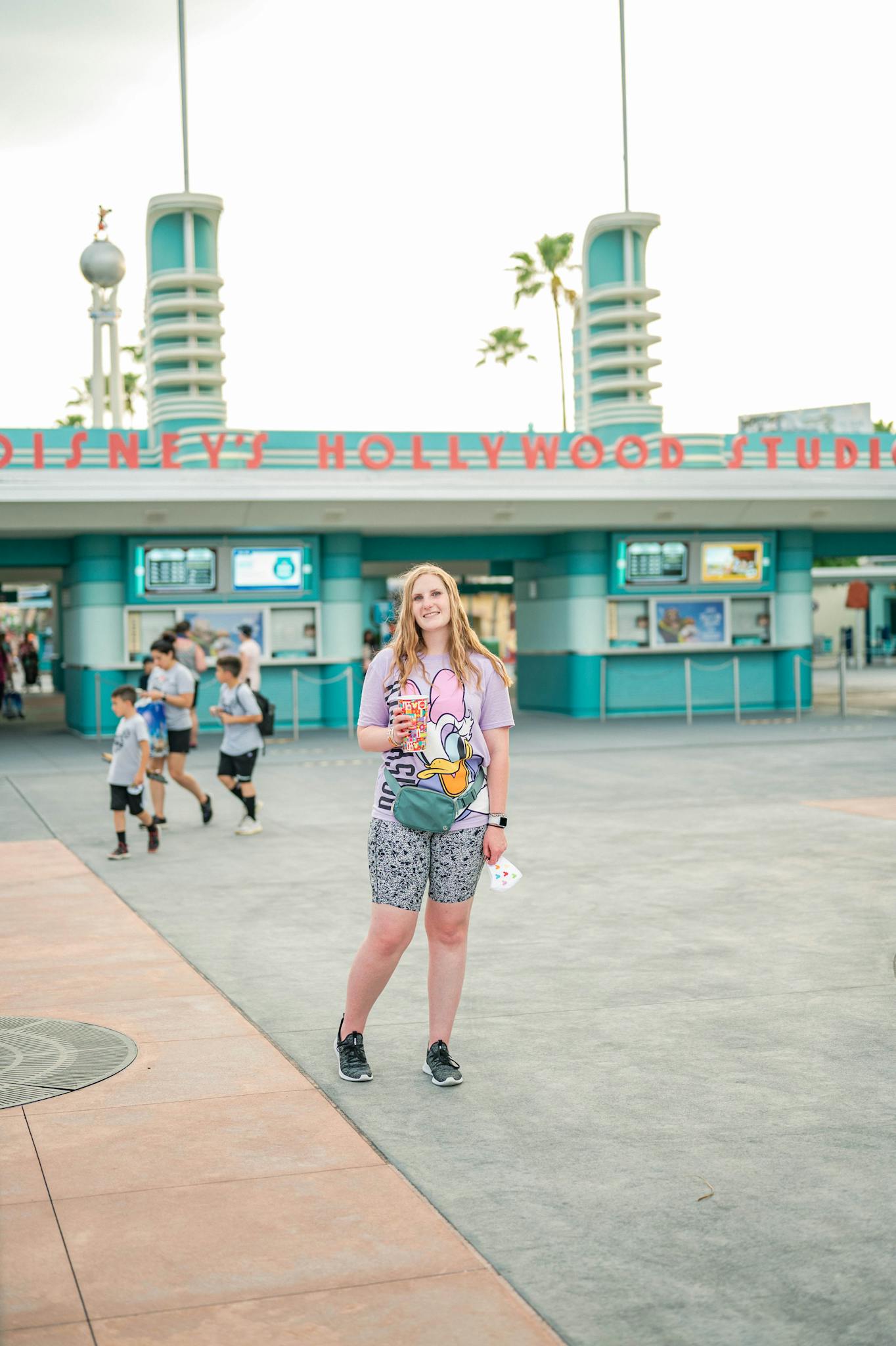 Smiling woman stands at Disney's Hollywood Studios entrance, embracing a joyful tourist experience.